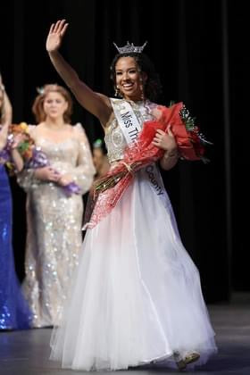  Nyah Hart crowned as Miss Thurston County 2024, wearing a sparkling tiara and sash, standing with a radiant smile. Holding a bouquet of flowers and waving at the crowd 